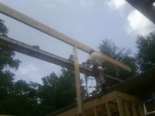 Carpenter setting a ridge beam over a new addition frame — Ice Dam Removal by Roofing Brothers in Bronson