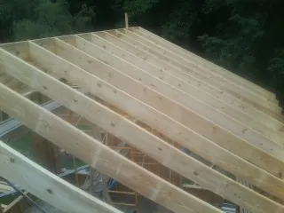 New roof rafters set over an addition before sheathing in Bronson