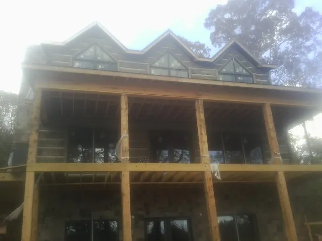 Dormers and porch framing on a large log home under construction — Roof Coating work by our crew in Bronson