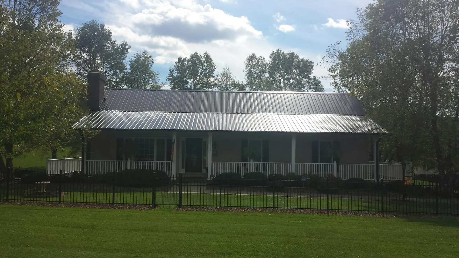 Gray metal roof on a brick ranch with a full width front porch — Gutter Guard Installation work by our crew in Bronson