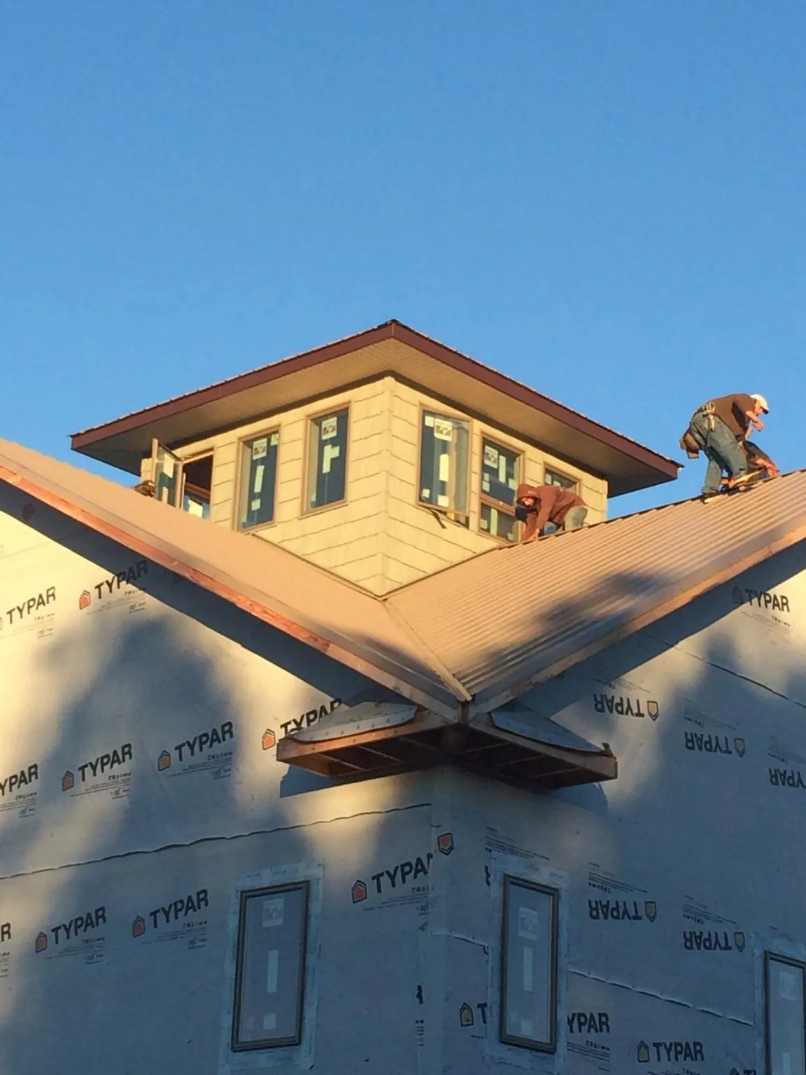 Roofers working around a rooftop cupola on a new metal roof at sunset — Roof Waterproofing in Bronson by Roofing Brothers
